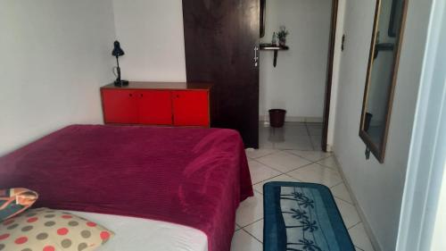 Casa do Roberto في جاراغوا دو سول: غرفة نوم صغيرة مع سرير وخزانة حمراء