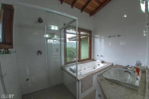 a bathroom with a tub and a sink and a shower at Bangalôs do Rosa-Praia do Rosa in Imbituba