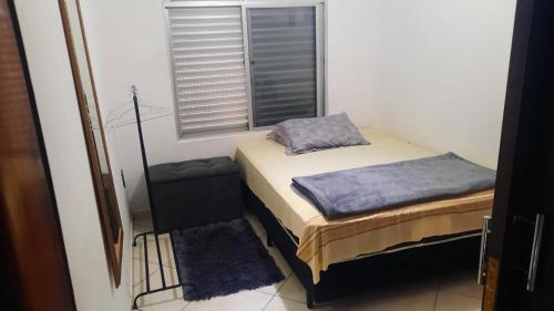 Casa do Roberto في جاراغوا دو سول: غرفة نوم صغيرة بها سرير ونافذة