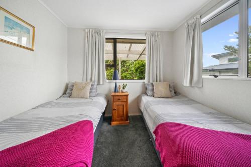 2 Betten in einem Zimmer mit 2 Fenstern in der Unterkunft Lagoon Haven - Waikanae Holiday Home in Paraparaumu Beach