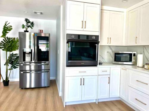 a kitchen with white cabinets and a stainless steel refrigerator at Spacious & Modern 4B3B house in Pasadena in Pasadena