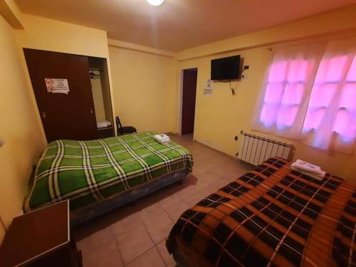 a bedroom with a bed and a tv and a window at Lago Buenos Aires in Perito Moreno