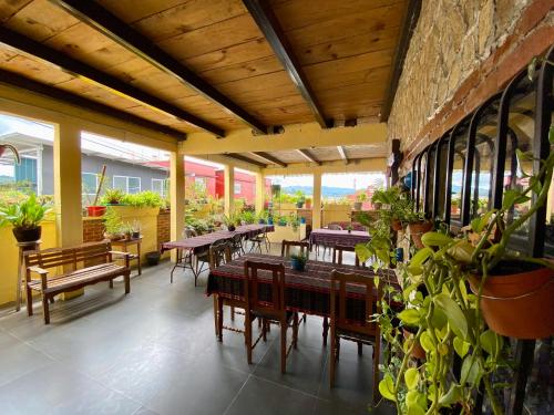 un restaurante con mesas de madera, sillas y plantas en El Calvario Hostal en Cobán