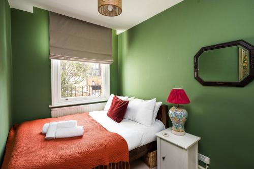 a green bedroom with a bed and a window at Elegant and Peaceful 2BD apt - Barons Court/London in London