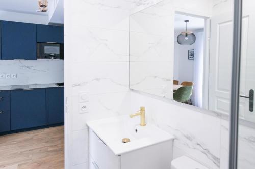 ein weißes Badezimmer mit einem Waschbecken und einem Spiegel in der Unterkunft Le Saint-Germain - Porte d'Orléans - Cité Universitaire Paris 14 in Gentilly