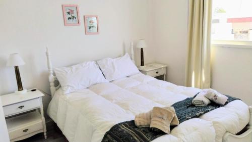 a white bed in a bedroom with two night stands at Pepa in Tandil