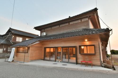 a house with two red chairs in front of it at Togiso 能登の古民家宿 in Togi