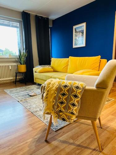 a living room with a yellow couch and a blue wall at Centro-ist-nicht-mehr-weit in Oberhausen