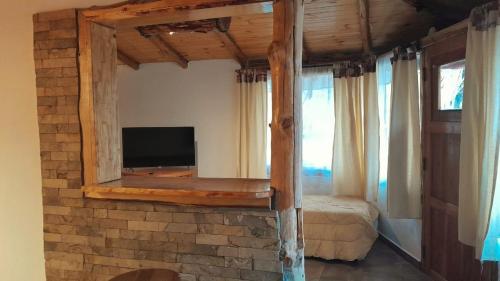 1 dormitorio con TV en una pared de ladrillo en Complejo turístico Nahuel pan en Esquel