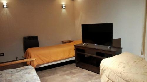 a bedroom with two beds and a flat screen tv at Complejo turístico Nahuel pan in Esquel