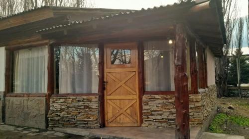 mały dom z drewnianymi drzwiami i oknami w obiekcie Complejo turístico Nahuel pan w mieście Esquel