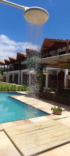 a swimming pool with a fountain in front of a house at icaraizinho villa soleil in Amontada