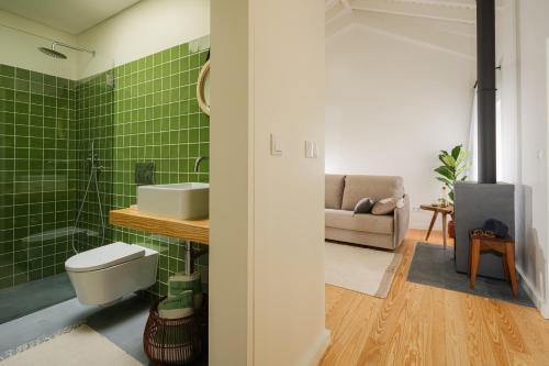a bathroom with a toilet and a green tiled wall at ENTRE MUROS - Turismo Rural - Casa com jardim e acesso direto ao mar in Ribeira Grande