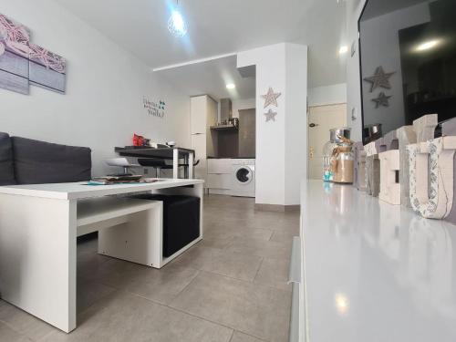 a white room with a desk and a kitchen at Apartamento Luna de Zahara - Situado en la zona tranquila del pueblo a 3 min de la playa y ocio in Zahara de los Atunes