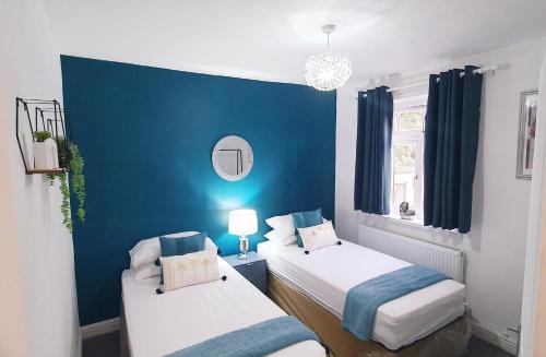 2 camas en una habitación con una pared azul en Stourbridge House, Luxurious 3 Bedrooms - Ideal Location for Contractors and Families, Free Parking, Fast Wifi, Sleeps up to 8 en Lye