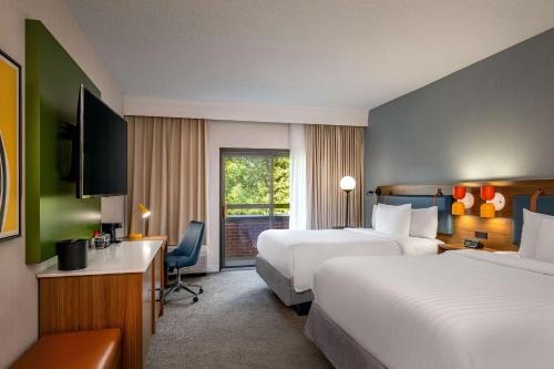 a hotel room with two beds and a television at Sonesta Select Boston Foxborough Mansfield in Foxborough