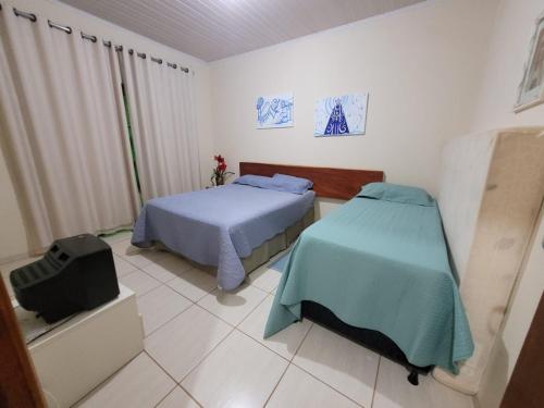 a bedroom with two beds and a tv in it at Casa para sua família in Bonito