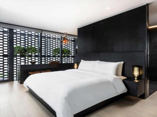 a bedroom with a large white bed and a black wall at The Temple House in Chengdu