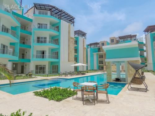 a swimming pool with a table and chairs in front of a building at Hermoso apartamento 1 hab a pasos de la playa in Punta Cana