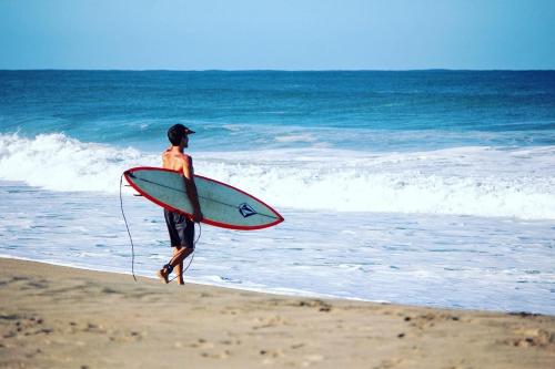 a man walking on the beach with a surfboard at Casa Daikiri in Puerto Escondido
