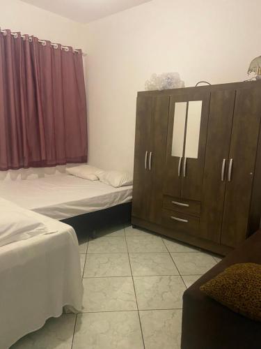 a room with two beds and a dresser in it at Espaço Verde in Vitória