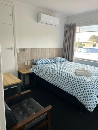 a bedroom with a bed and a chair and a window at Holiday Room in Chartwell in Hamilton