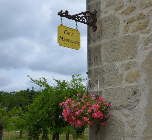 a sign on the side of a stone wall with flowers at Chez Madeleine in Saint-Colomb-de-Lauzun