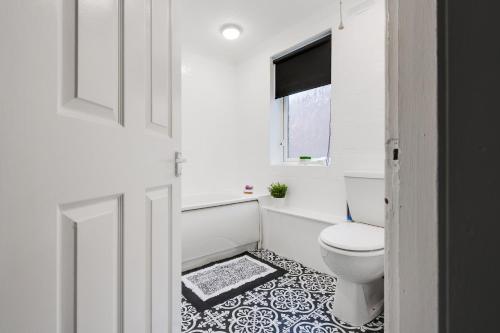 a white bathroom with a toilet and a window at Beautiful Anfield home close to LFC stadium in Liverpool