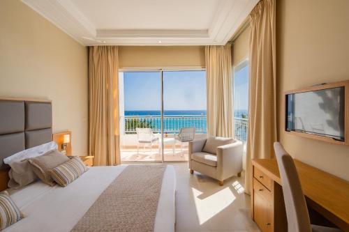 a bedroom with a bed and a television and a balcony at Hotel Bel Azur Thalasso & Bungalows in Hammamet