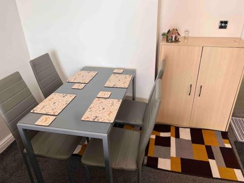 a dining room table with four chairs and a cabinet at Lincoln View. Sleeps 6. Balcony. Self check-in. in Lincolnshire