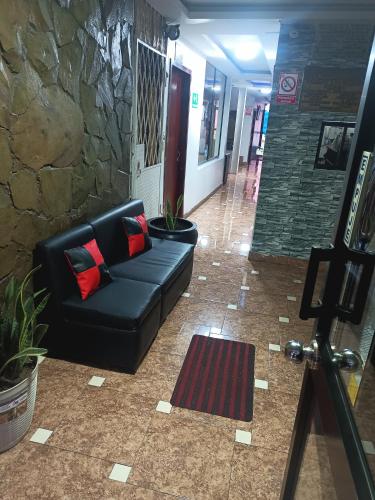 un divano in pelle nera nella hall con un muro di pietra di Hotel Richard's a Riobamba