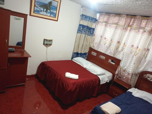 a small bedroom with a red bed and a mirror at Hotel Richard's in Riobamba