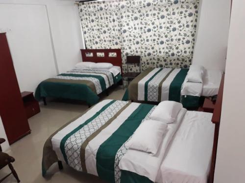 a bedroom with three beds in a room at Hotel Richard's in Riobamba