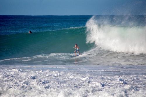 a woman riding a wave on a surfboard in the ocean at Casa Daikiri in Puerto Escondido