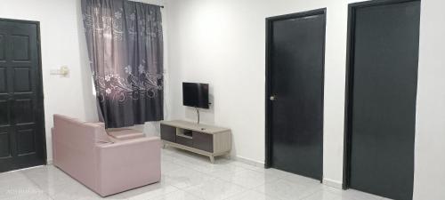 Cette chambre dispose d'une chaise, d'une télévision et d'une porte. dans l'établissement Santai Homestay, à Tuaran