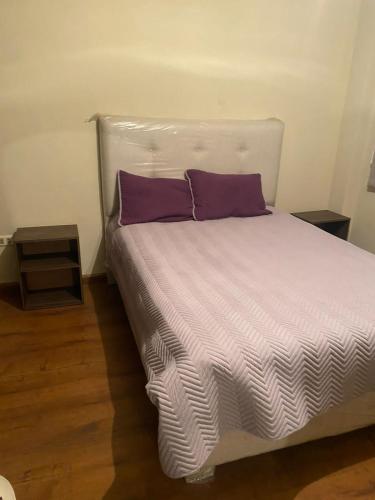 uma cama com almofadas roxas num quarto em Hermoso Departamento Familiar em Cochabamba