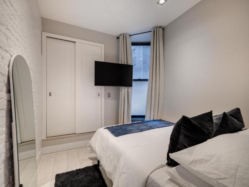 1 dormitorio con 1 cama y TV en la pared en Cozy & Convenient Midtown Apartment! en Nueva York