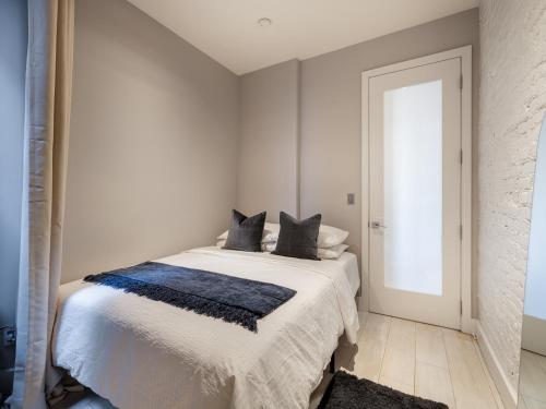 a white bedroom with a bed with black pillows at Cozy & Convenient Midtown Apartment! in New York