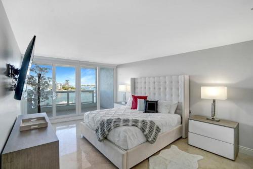 a white bedroom with a large bed and a window at Only in My Dreams! Direct Water View Luxury Condo in Miami