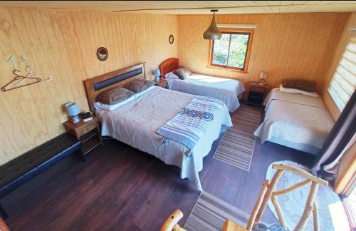 1 dormitorio con 2 camas y ventana en Hostal Turismo Allipen en Melipeuco