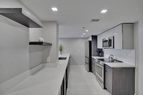 a large kitchen with white counters and appliances at A Wave From It All! Direct water views! in Miami