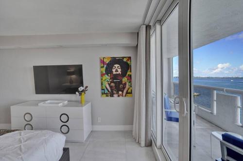 a white bedroom with a view of the ocean at A Wave From It All! Direct water views! in Miami