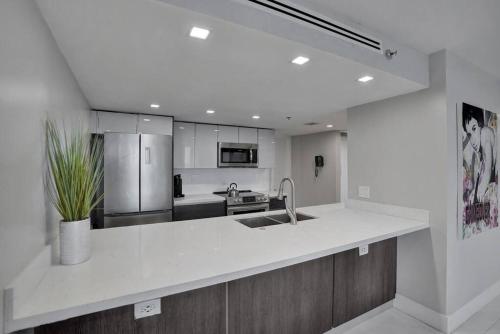 a white kitchen with a sink and a refrigerator at A Wave From It All! Direct water views! in Miami