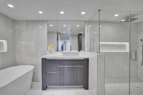 a bathroom with a tub and a sink and a shower at A Wave From It All! Direct water views! in Miami