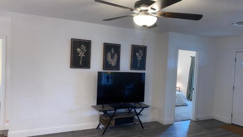 a living room with a flat screen tv and a ceiling fan at Entire cozy home in Madera