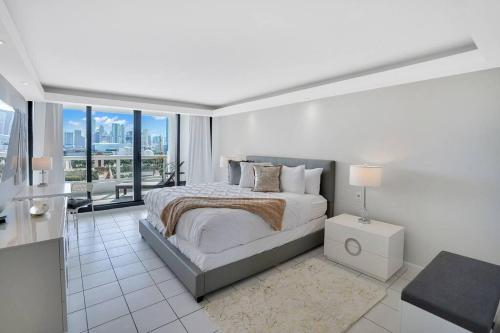 een witte slaapkamer met een bed en een balkon bij Sea Forever! Miami Skyline And Water Views in Miami