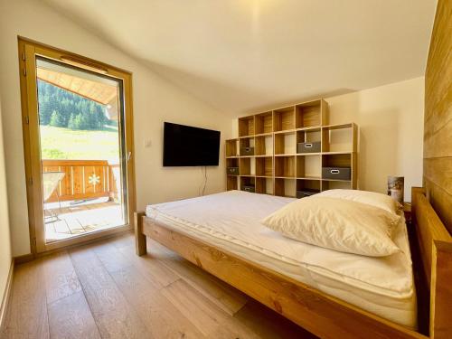 une chambre avec un lit et une grande fenêtre dans l'établissement Appartement neuf sur les pistes avec parking et wifi - FR-1-505-190, à Notre-Dame-de-Bellecombe