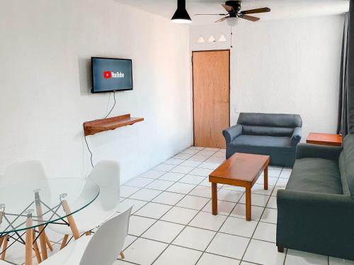 Departamentos 1E في بويرتو فايارتا: غرفة معيشة مع أريكة وتلفزيون على الحائط