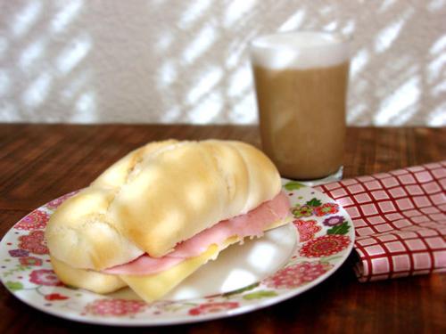 a sandwich on a plate on a table with a drink at Residencia Hostel in Vila Anastácio