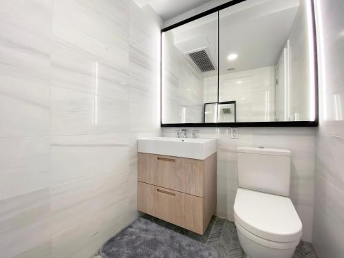 uma casa de banho com um WC, um lavatório e um espelho. em Private Garden Two Bedroom Residence in Luxury Condominium em Nova York